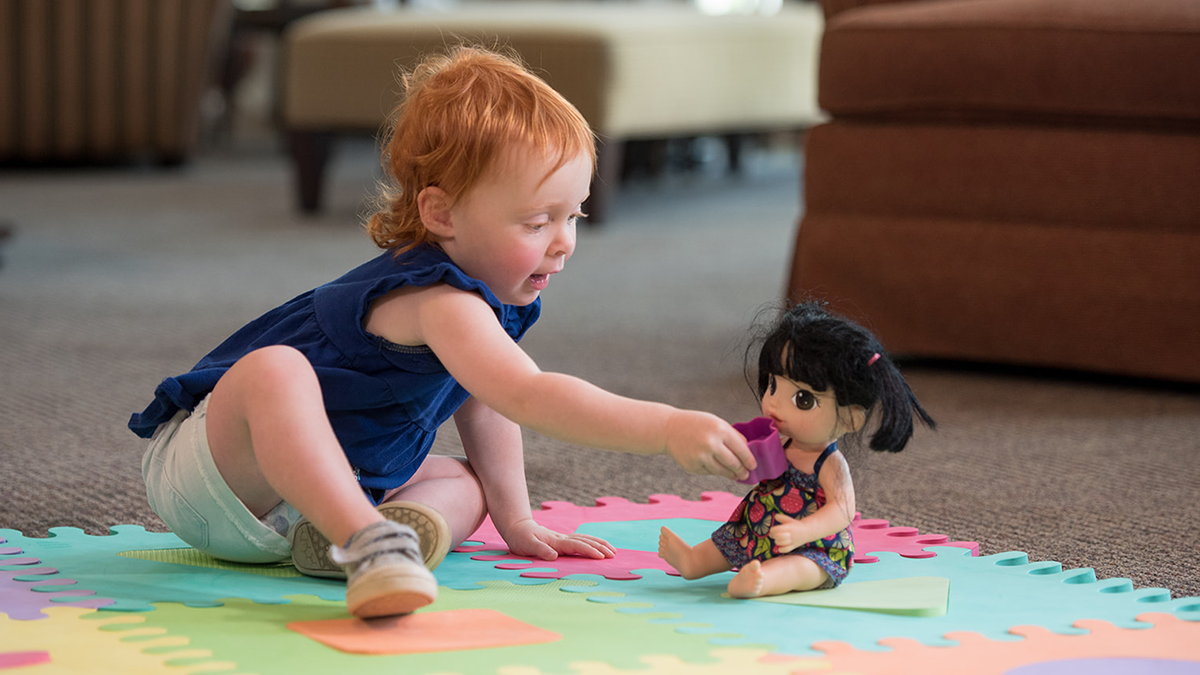 Toddler plays with her doll.
