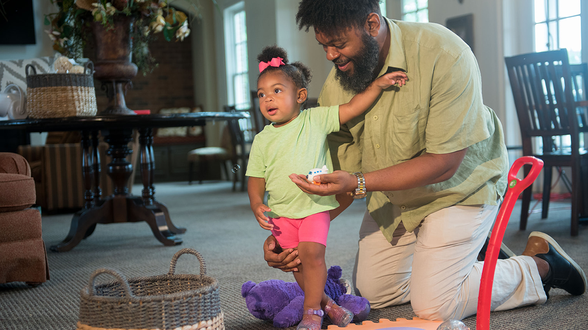 dad playing with daughter and toy on floor