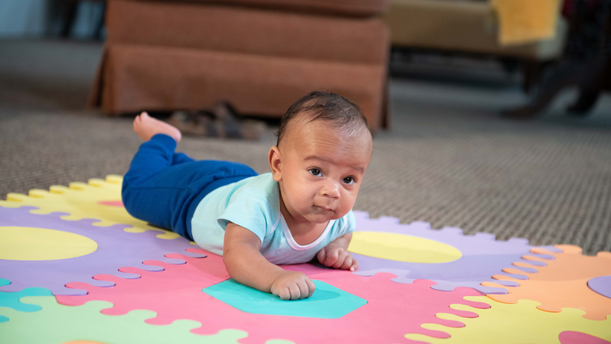 Baby lays on mat holding head up