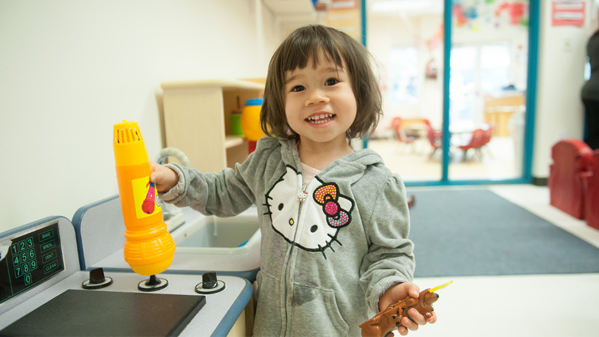 2 year old girl plays in a toy kitchen.