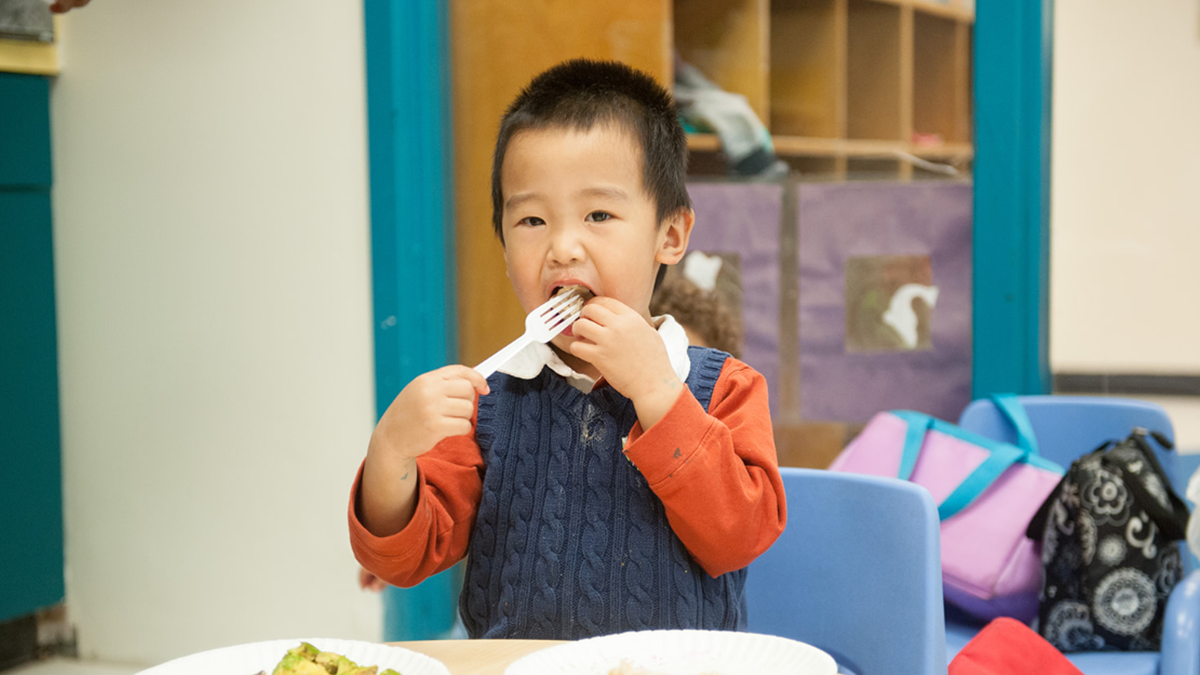 3 year old eats food using a fork.