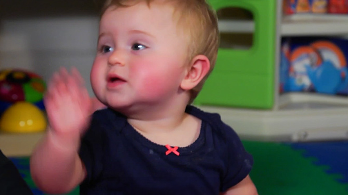 Niño de 1 año diciendo adiós con la mano.