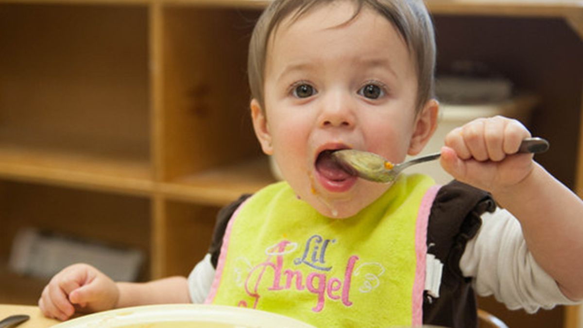 Niño de 18 meses comiendo con una cuchara.
