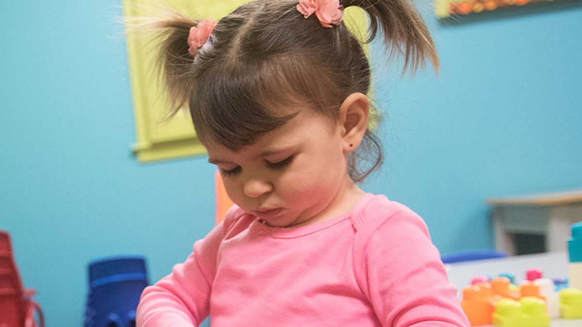 Niña de 30 meses jugando con un envase.