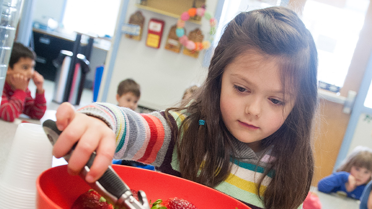 Niña de 4 años sirviéndose comida.