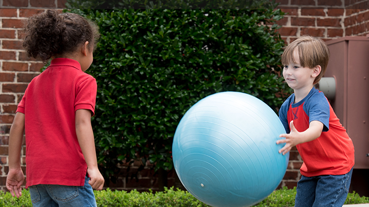 Niños de 5 años jugando con una pelota.