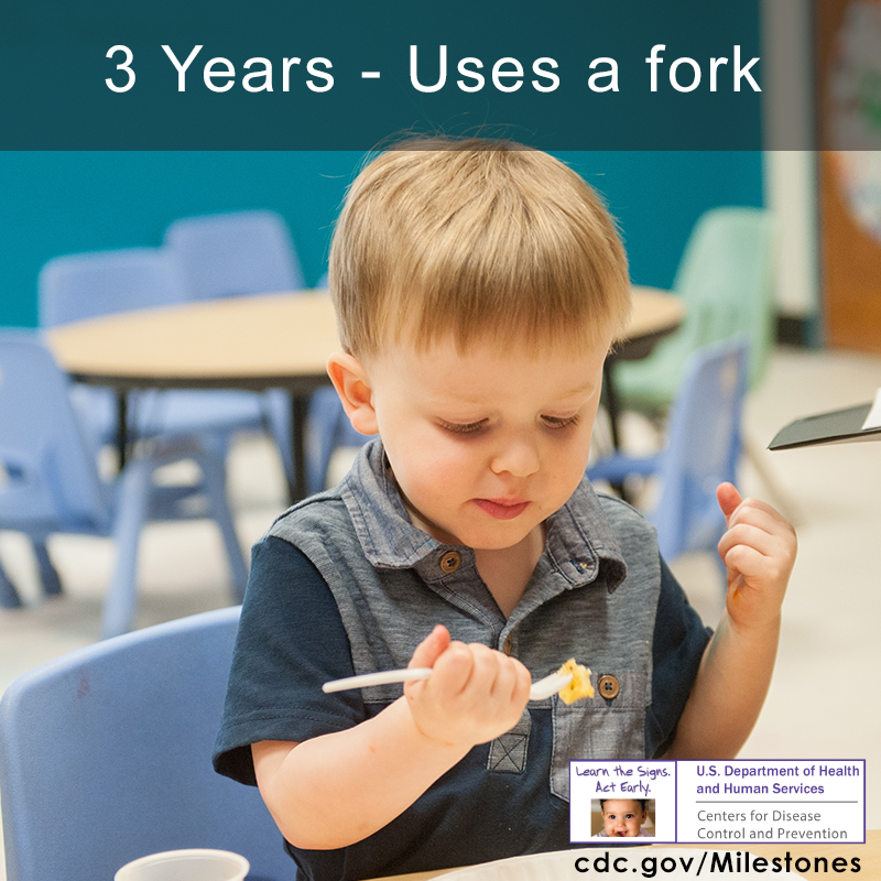 The boy in this photo is using a fork to eat some food, a 3 year milestone.