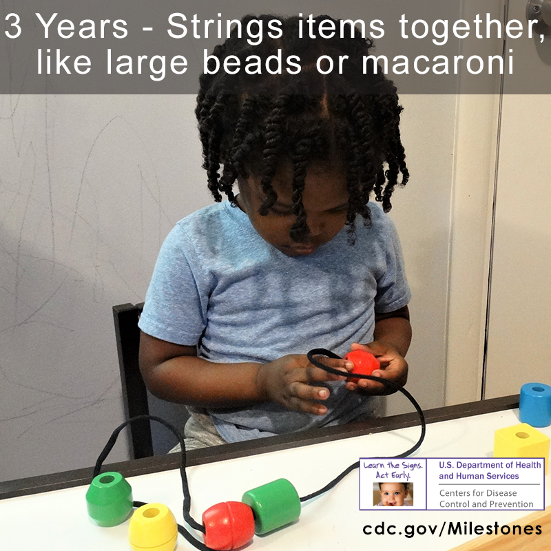 The child in this photo is stringing red, yellow, and red items together, 3 year milestone.