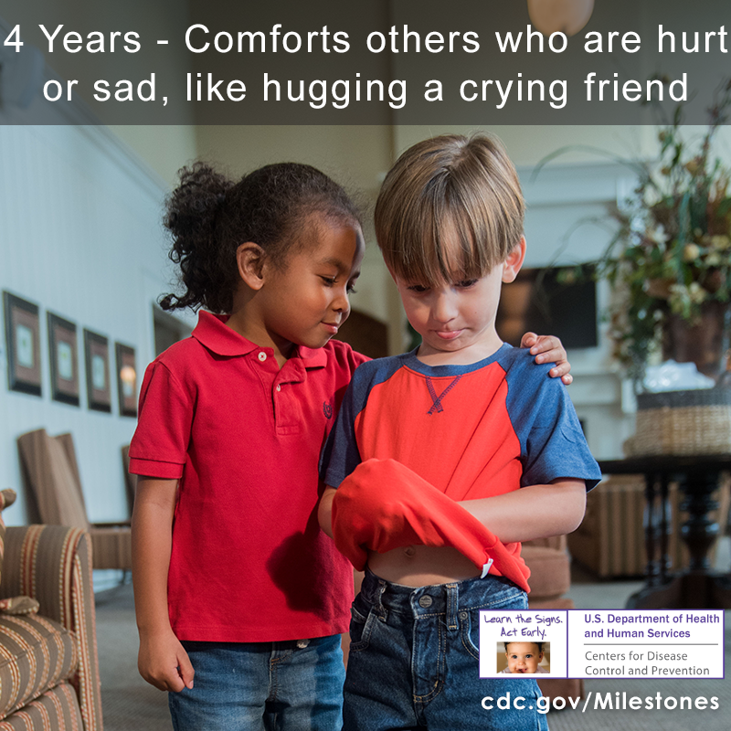 A child in a red shirt is comforting another child by putting their arm on their shoulder.