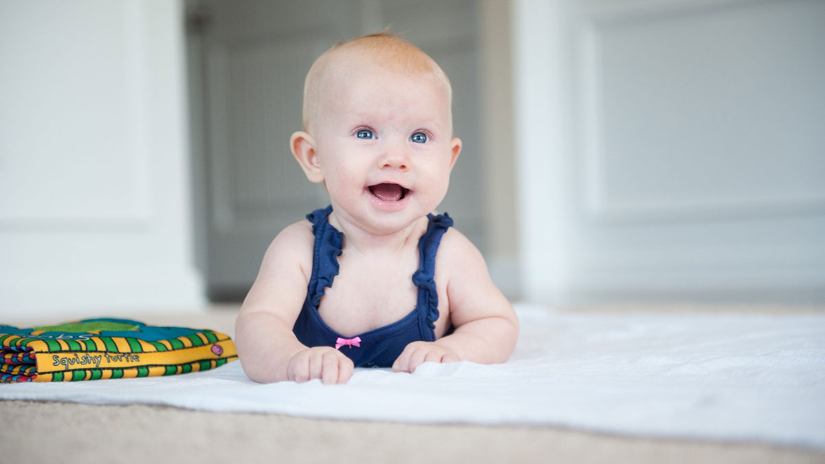 A happy baby lying on her stomach.