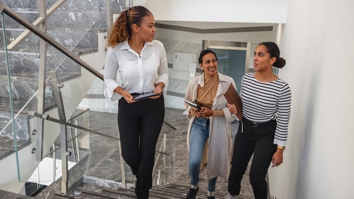A group of young professional women climbing the stairs in a workplace