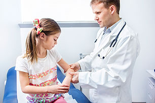Un médico examinando el codo de una niña