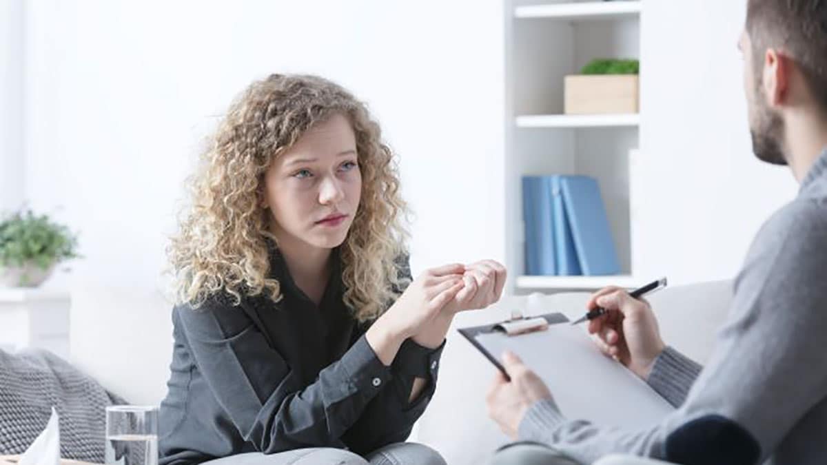 Young adult female patient talking with doctor