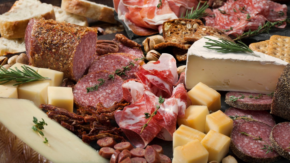A charcuterie board filled with cheeses and meats for appetizers.