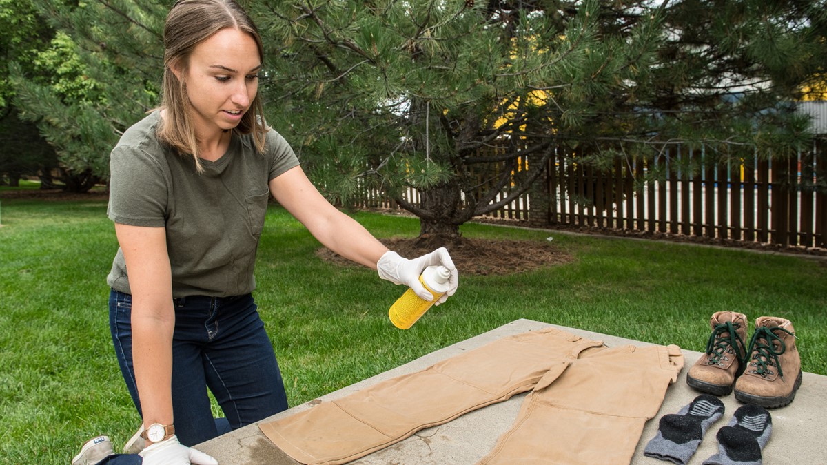 Woman treating clothing and gear with permethrin.