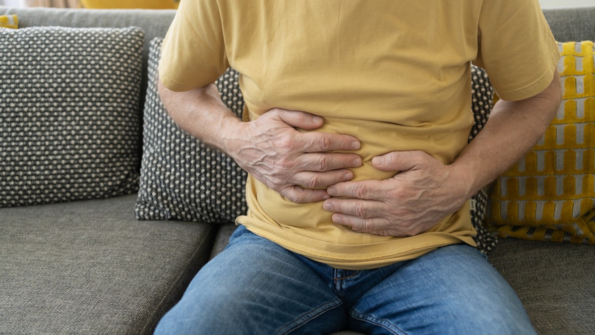 A man clutches his stomach, indicating painful symptoms.