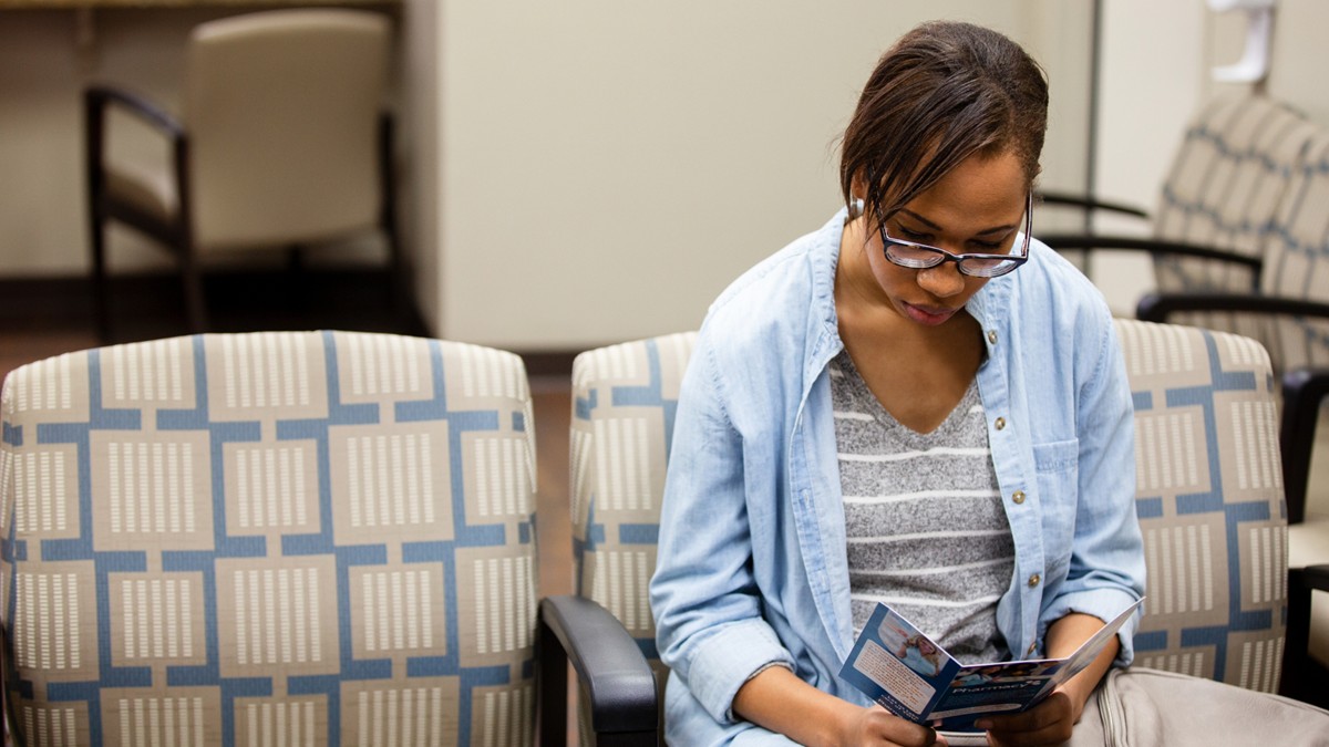 Woman reads an informational brochure in a healthcare provider's office.