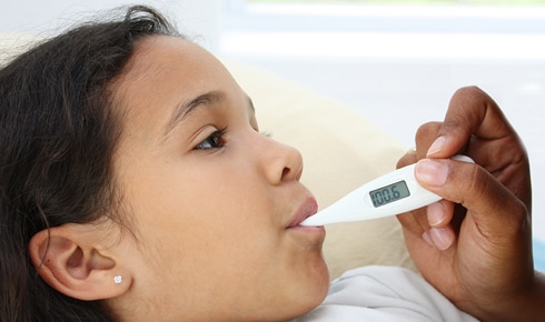 Young girl having her temperature taken with a thermometer