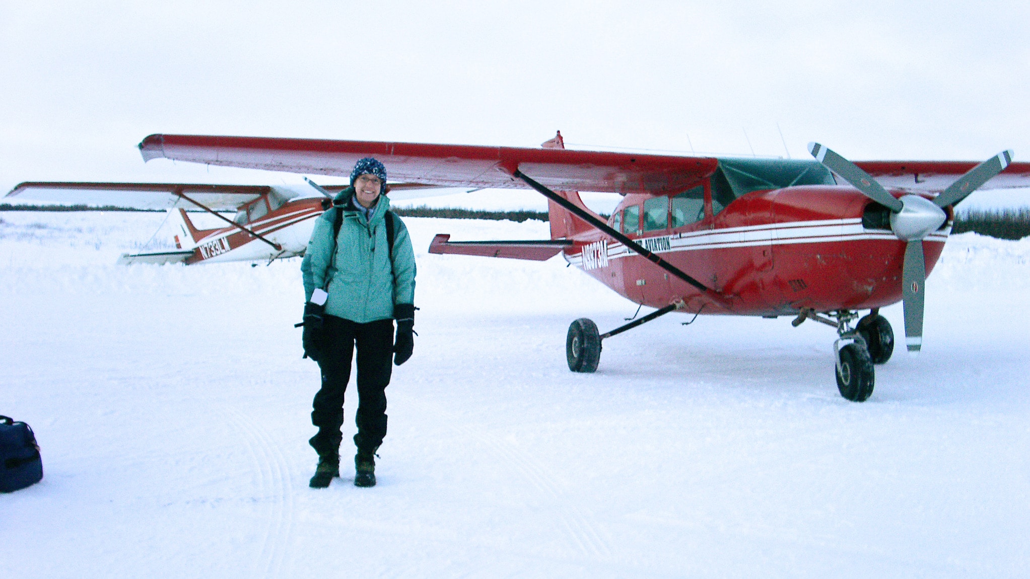 Woman stands by small plane in Alaska.