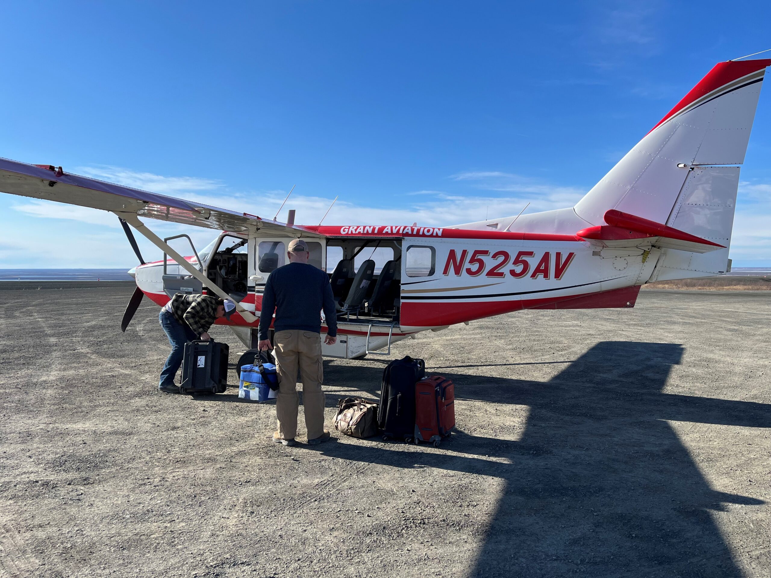 Two people loading baggage on to a small plane.