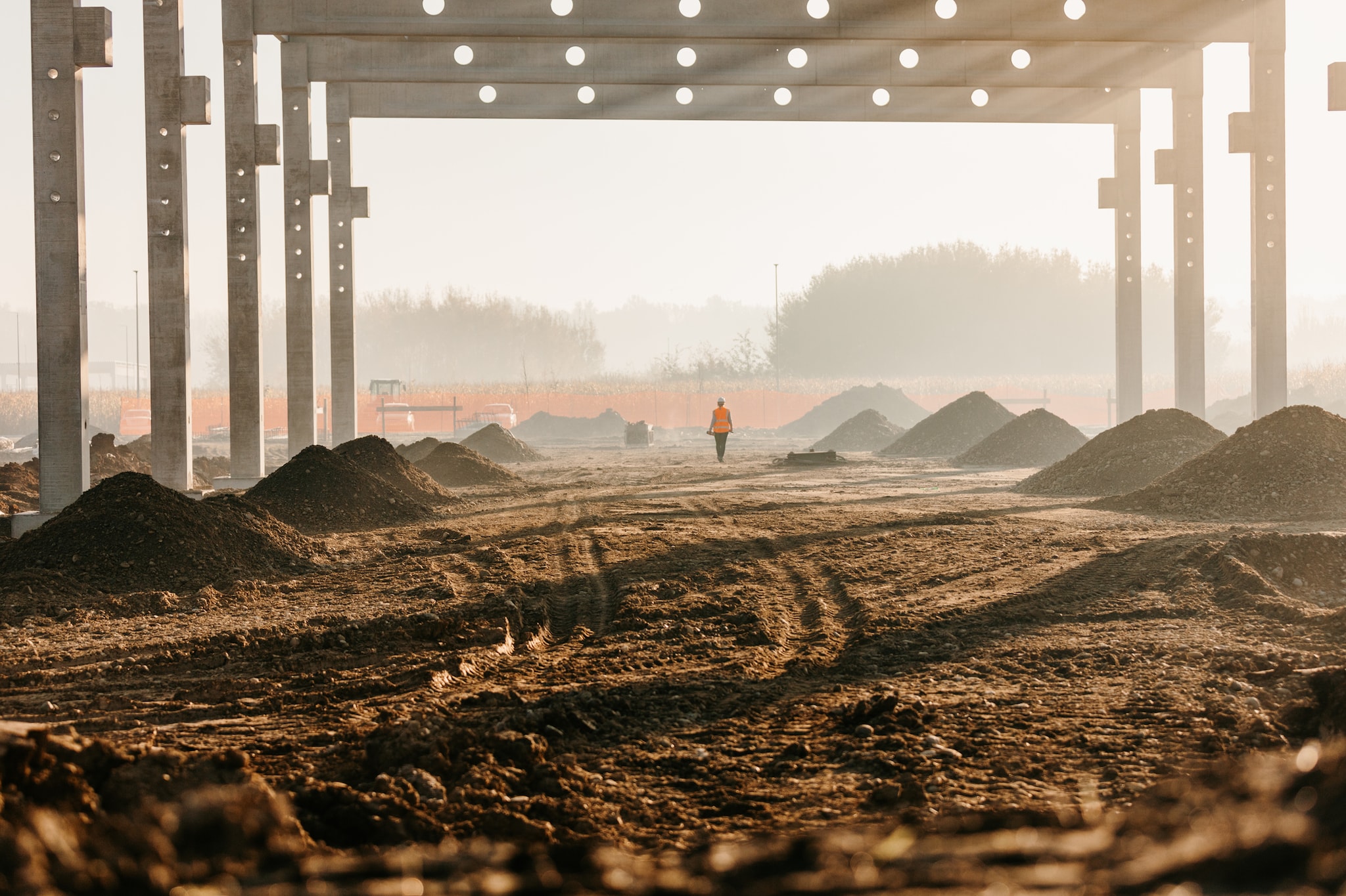 A construction site with a worker in the background and dust flying around.