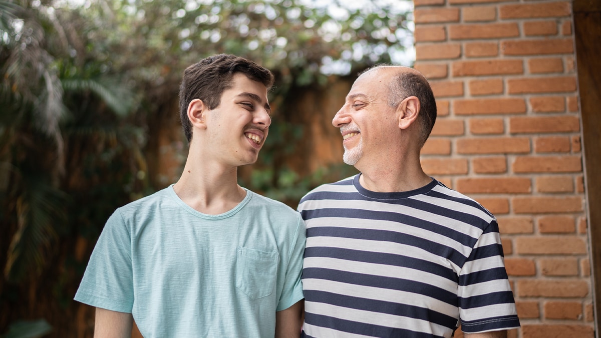 Father smiling with son that has a disability.