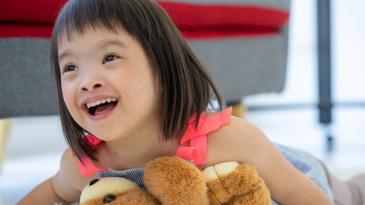 Niña con un osito de peluche sonriendo.