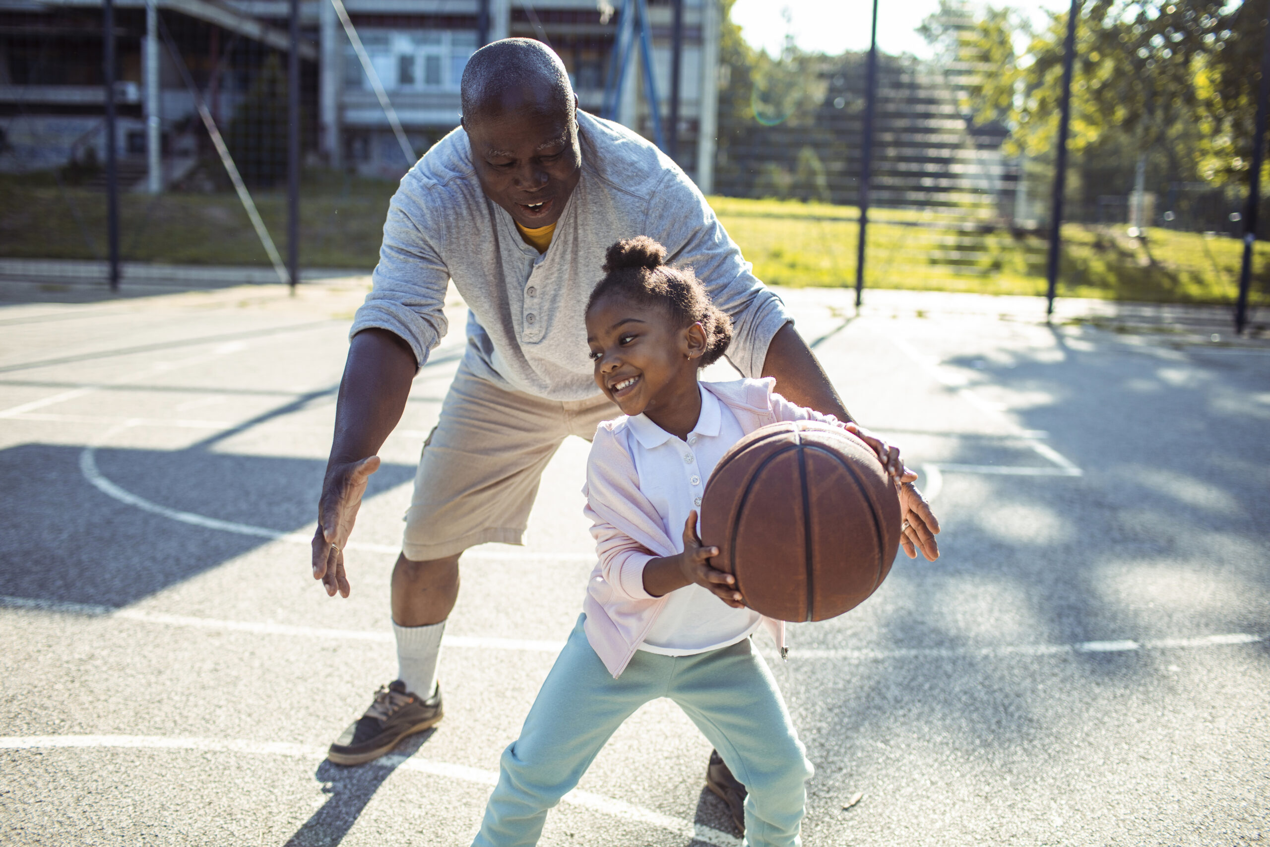 Child and grandparent playing basketball