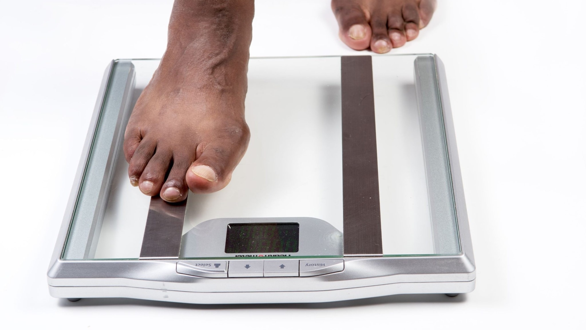 African American male feet stepping on electronic scales.