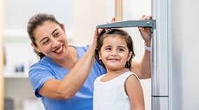 Health care professional measuring child's height