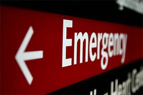 A red hospital emergency sign with an arrow pointing left