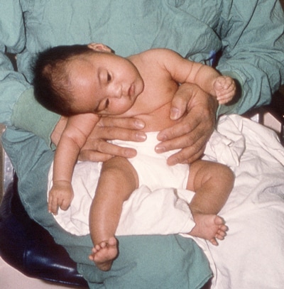 Doctor holding a baby in a sitting position.