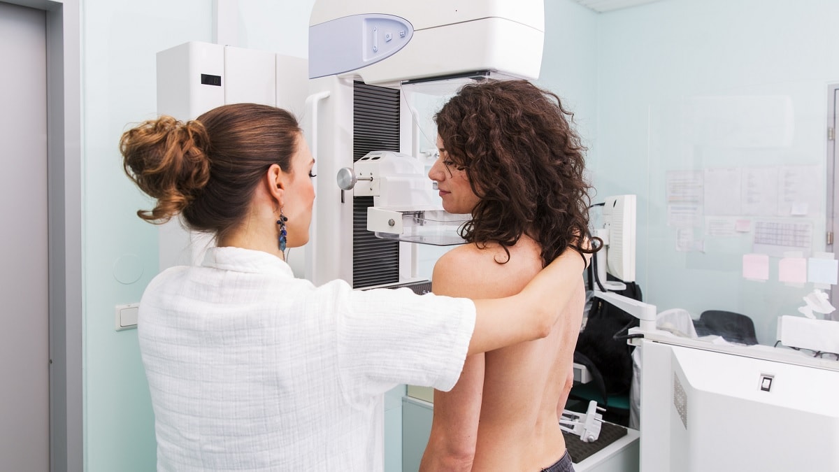 una enfermera posicionando a una mujer para una mamografía