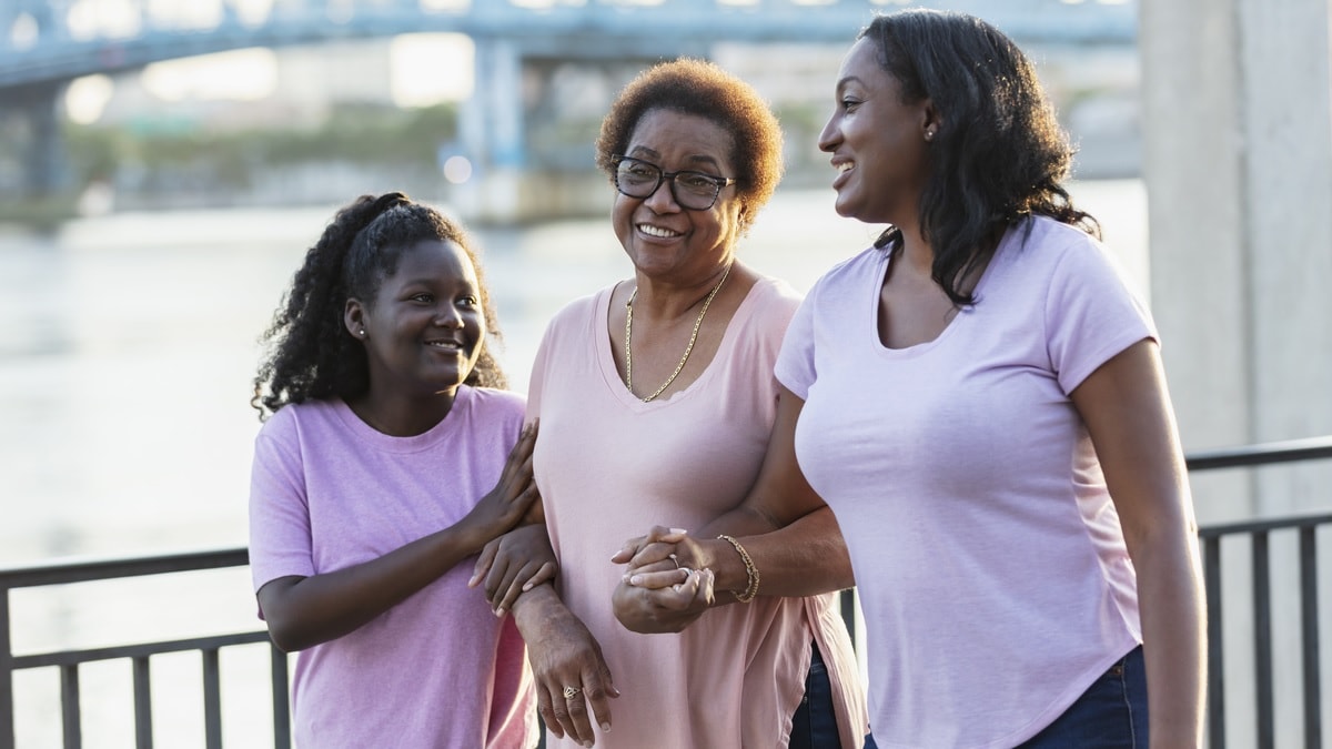 A grandmother, her adult daughter, and granddaughter walk outdoors