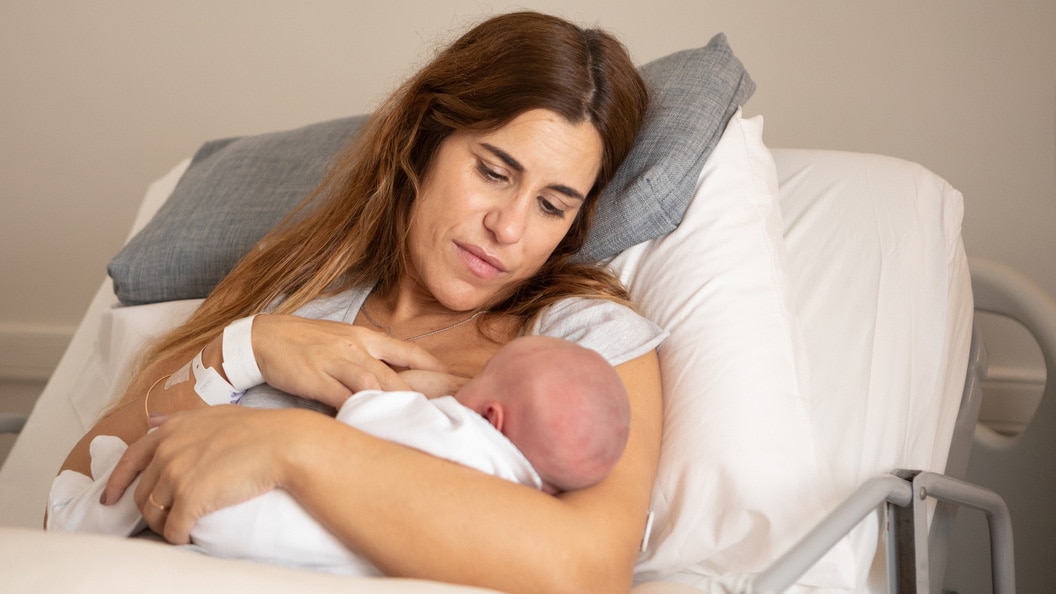 A newborn baby with their mom in a hospital bed.