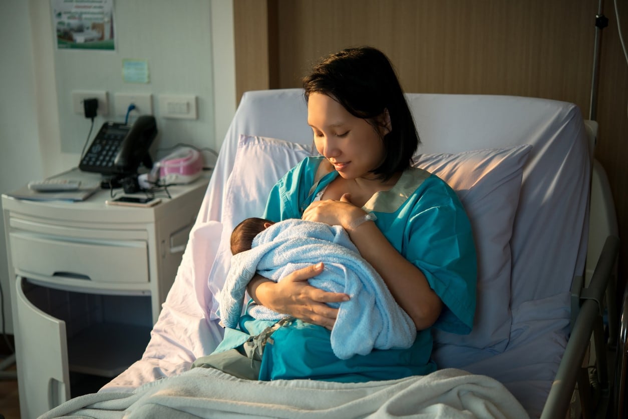 Mother breastfeeding newborn baby in hospital setting.