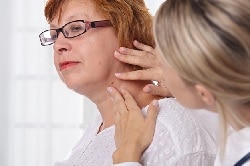 Foto de un doctor examinando un lunar en el cuello de una mujer