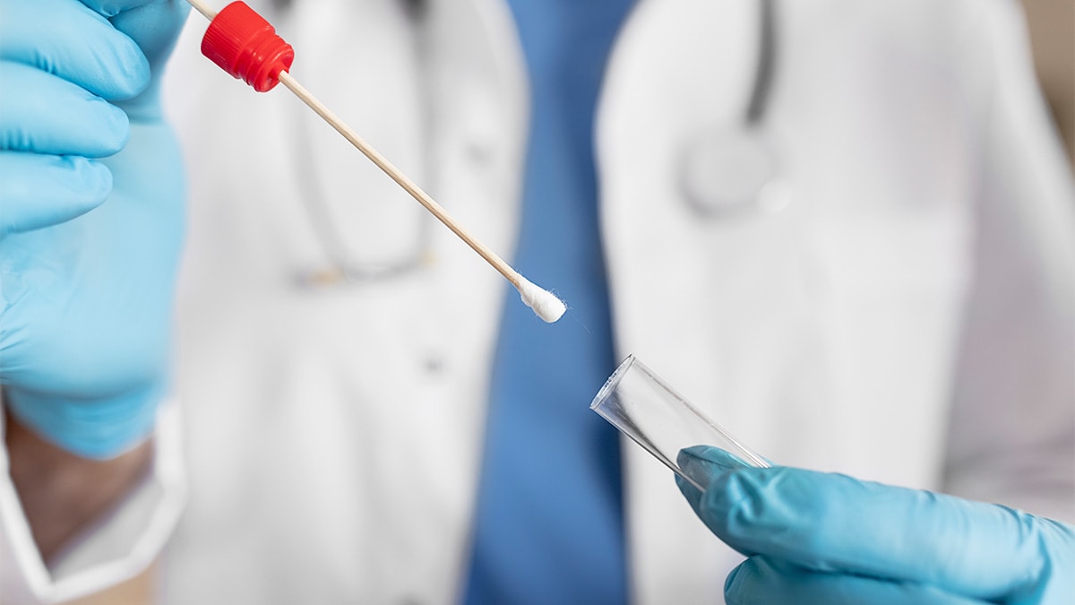 Photo of a healthcare provider holding a swab and test tube