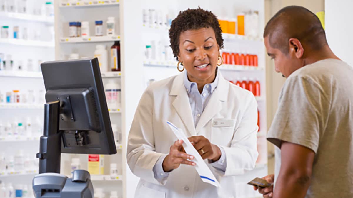 A female pharmacist talking to a male customer about a medication.