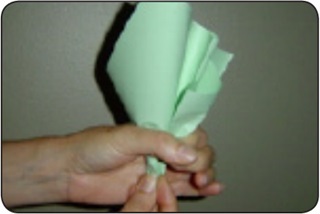 Una persona dobla hojas de papel verde para formar una col de papel.
