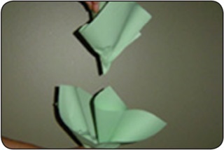 Una persona dobla hojas de papel verde para formar una col de papel.