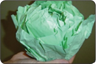 Una persona dobla hojas de papel verde para formar una col de papel.