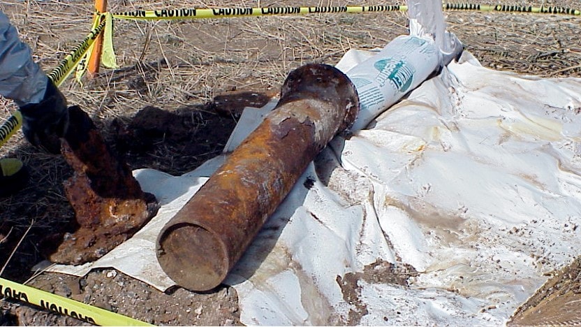 An image of a rusty munition on a tarp on the ground.