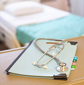 Stethoscope and binder on a table in the hospital room.