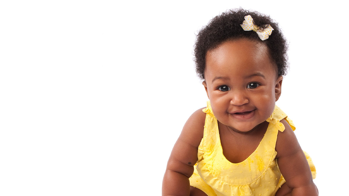 Infant with yellow shirt smiling