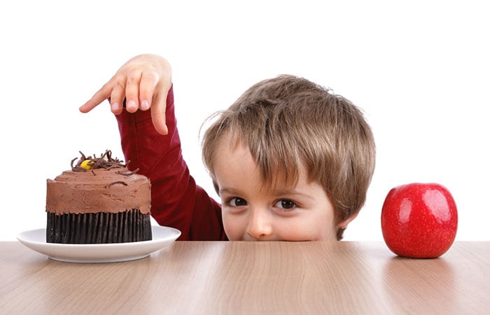 A young boy choosing between a cake or an apple