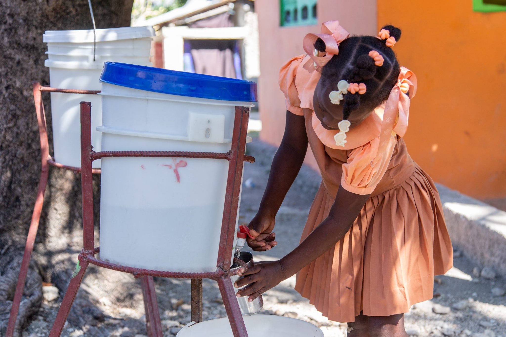 Young girl in Haiti fills her glass with clean water from a container