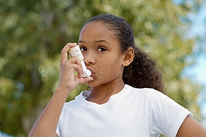 Girl (7-9) using inhaler, outdoors - Air Pollution