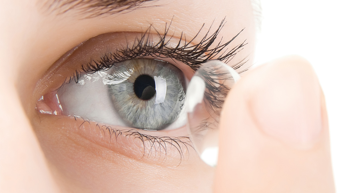 Woman with grey eyes putting on a contact lens