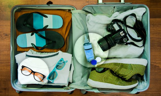 Open suitcase with clothing items and a contact lens travel kit